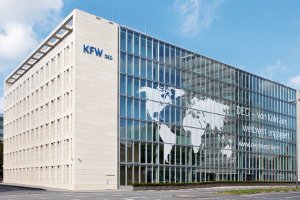 Helles Bürogebäude vor blauem Himmel, Aufschrift: DEG - von Köln aus weltweit engagiert.