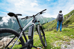Mountainbiker mit E-Mountainbike genießt den Ausblick in die Berge.