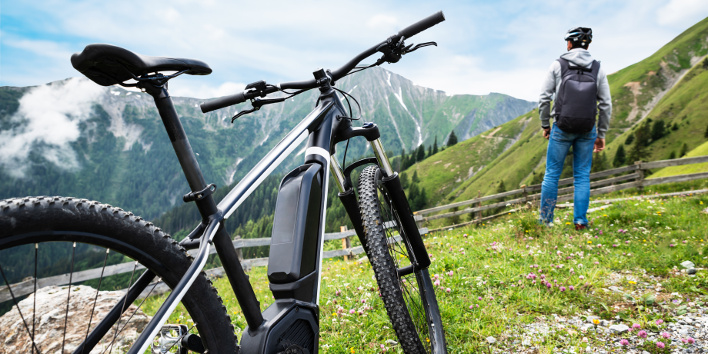 Mountainbiker mit E-Mountainbike genießt den Ausblick auf die Berge.