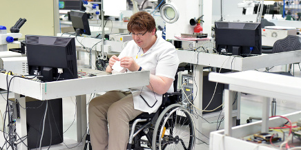 Angesteller im Rollstuhl montiert Elektronikomponenten